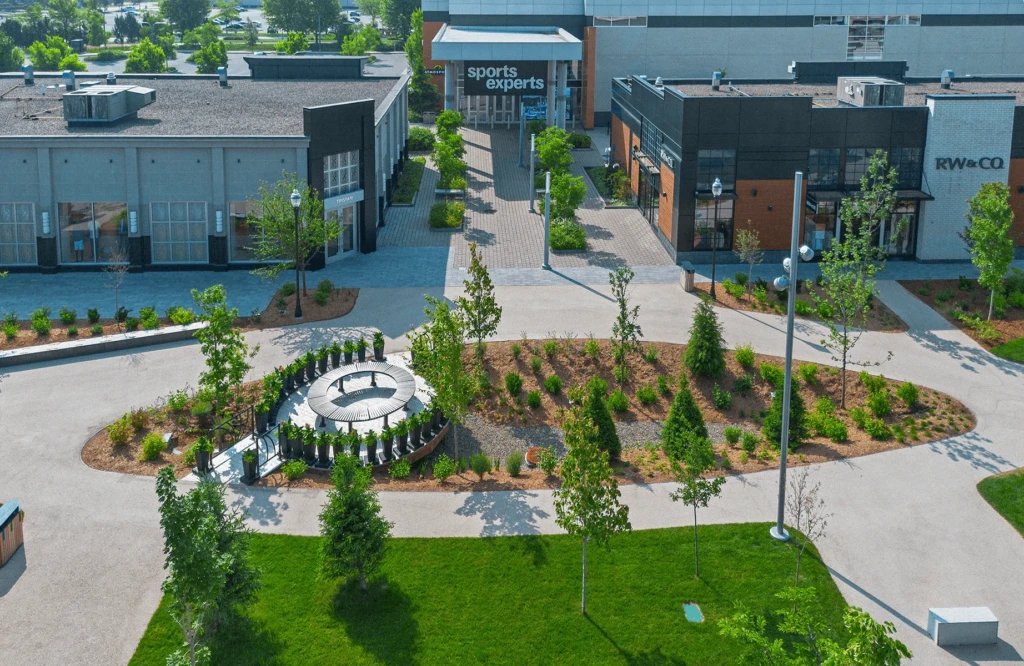 Sentier paysager et noue de drainage naturelle au centre de l'allée des lumières, avec paillis et arbustes, réalisation urbaine exécutée Services Paysagers Dominique Filion.